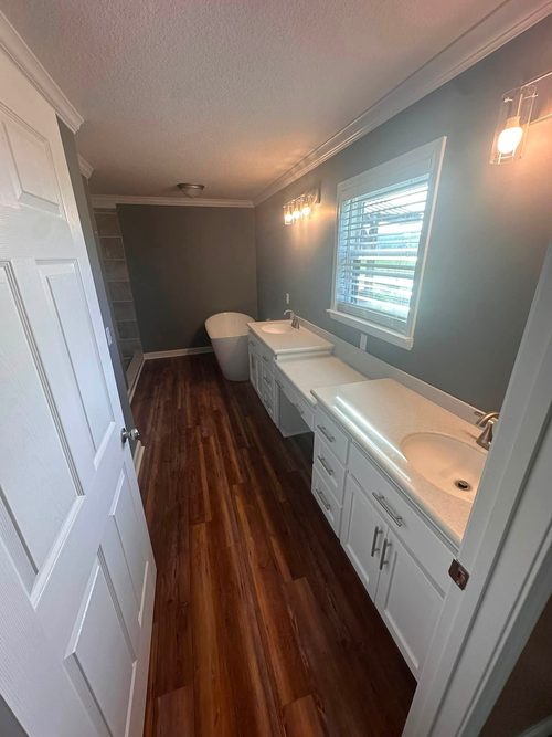 The finished master bathroom with a double vanity and a freestanding tub.